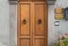 porte d'entrée en bois marron sur façade de pierre grise avec éléments décoratifs