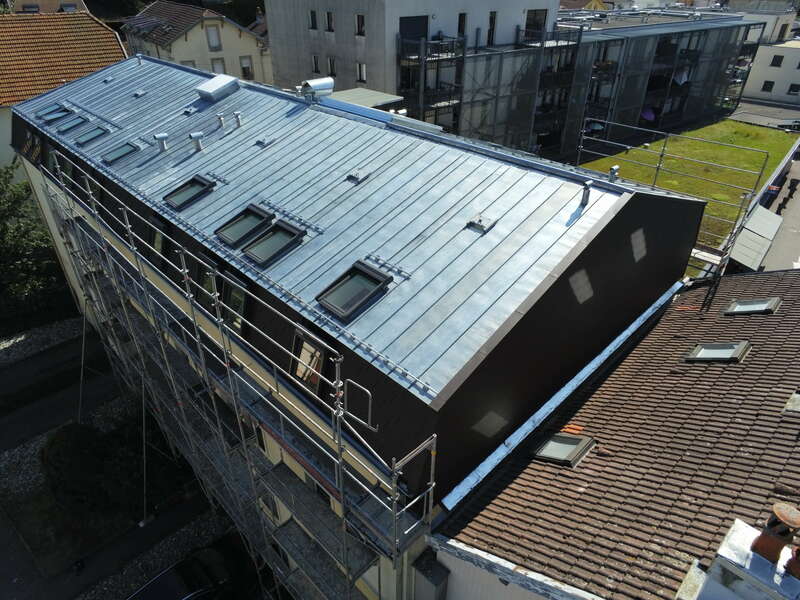 Copropriété à EPINAL (88) – Rénovation de la toiture par une couverture en zinc à joint debout, fenêtres de toit et bardeaux aluminium Prefa