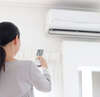 Femme utilisant télécommande pour unité murale climatisation