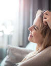 femme pensive sur canapé avec lumière naturelle