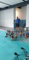 Coach sportif guidant enfants en piscine intérieure pour kinésiologie