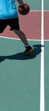 Homme dribblant ballon basket sur terrain vert extérieur