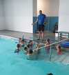 Entraîneur corrige technique crawl au bord piscine intérieure