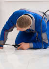 Technicien en uniforme appliquant traitement nuisibles sol carrelé