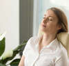 Femme assise les yeux fermés en posture de méditation pour rééquilibrage énergétique et harmonie intérieure