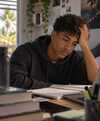 Jeune homme concentré travaillant au bureau avec cahier et ordinateur