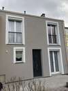 Façade de maison avec enduit gris et encadrements blancs