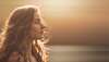 Femme en profil cheveux illuminés par soleil mer en arrière-plan