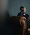 Homme seul, la main sur le visage, assis dans un fauteuil