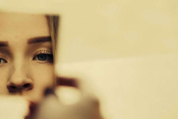 femme observant son reflet dans un fragment de miroir