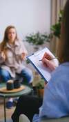Femme praticienne psychothérapie assise à bureau avec ordinateur