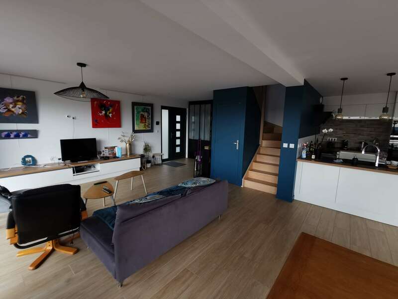 pièce à vivre canapé bleu fauteuil noir parquet escalier bois mur bleu cuisine ouverte 