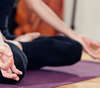méditation sur tapis violet, mur clair, objet orange en arrière-plan