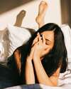 femme fatiguée au réveil allongée au lit avec les mains sur les yeux