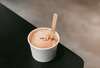 Glace pêche rose pâle dans pot avec cuillère en bois
