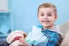 Enfant au fauteuil dentaire tenant un modèle de mâchoire, orthodontie pédiatrique