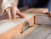 Mains guidant une planche vers une scie circulaire en atelier