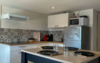 Cuisine moderne du logement de Rémi, avec îlot central, plaques de cuisson, hotte, four et micro-ondes.