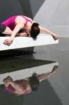 Femme en position de yoga agenouillée sur dalle de béton reflet visible bien-être et harmonie