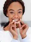 Gouttière d'alignement invisible tenue par une patiente souriante
