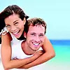 Couple souriant sur plage illustrant sourire esthétique adulte
