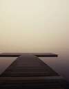 Jetée en bois sur eau calme dans brouillard apaisant