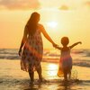 mere avec son enfant et coucher de soleil sur la plage