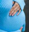 Femme enceinte au premier trimestre tenant son ventre bleu clair