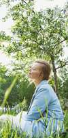 Femme détendue dans parc fleurs blanches santé bienveillance