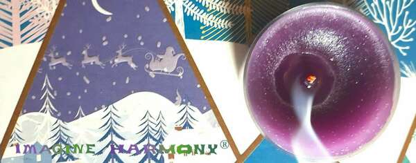 Une bougie violette s'éteint. Sa flamme rougeoit encore et sa fumée s'échappe. A coté d'elle, un ciel violet couvre un paysage enneigé de sapins couverts de neige.