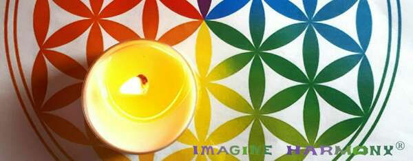 Une fleur de vie multicolore accueille une bougie jaune qui brûle, parfumée aux huiles essentielles. 