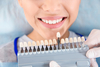 Jeune femme souriante comparant teinte dents facettes pelliculaires