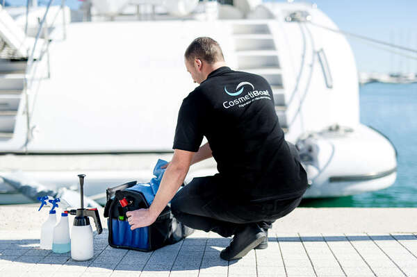 Expert d’entretien bateau CosmétiBoat accroupi sur quai devant outils