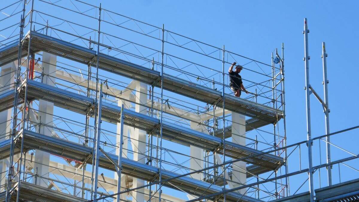 Reprise du passé assurance décennale : ouvrier sur un échafaudage de chantier de construction sous un ciel bleu