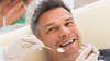 Homme souriant en fauteuil dentiste soins dentaires adultes