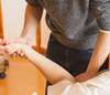 thérapeute manipule le bras d'un patient en consultation