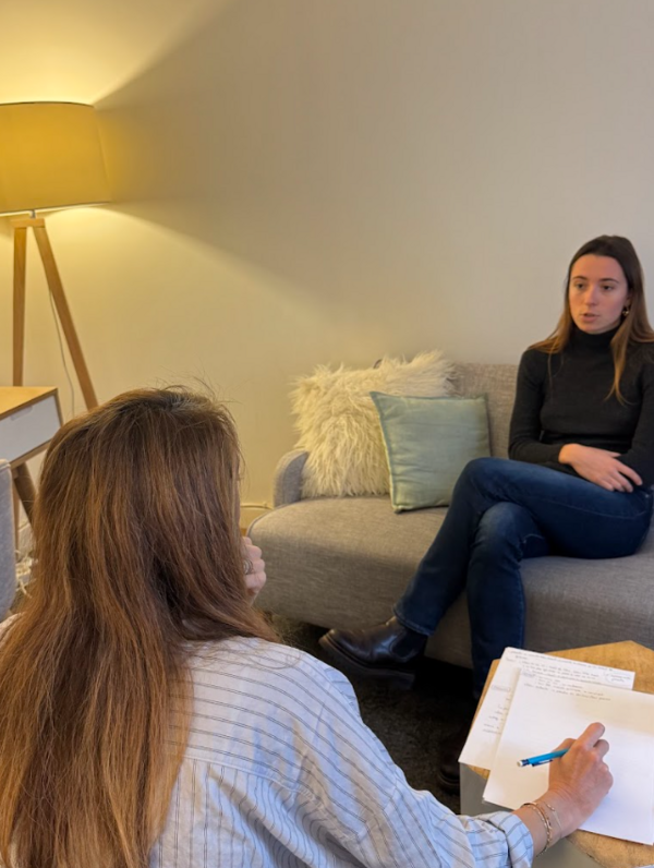 Amélie Clergue Vaurès, de dos, prend des notes face à une femme assise sur le canapé du cabinet