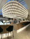 Vue d'ensemble du bar comptoir coiffé d'une structure métallique suspendue au plafond et à laquelle sont  accroché des pages textile blanche 