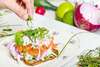 Herbes ciselées déposé sur un plat de saumon et légumes frais illustrant la diététique en collectivité
