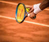 Mains tenant raquette tennis balle jaune terre battue