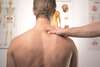 Chiropracteur traitant point de pression sur dos homme torse nu