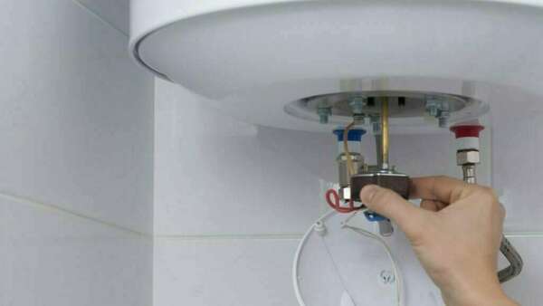 On voit une main entrain de réparer un ballon d'eau chaude 