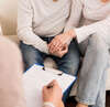 Psychologue prenant notes séance thérapie familiale parents
