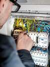 Technicien en intervention dépannage électrique tableau câbles multicolores
