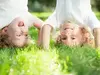 Deux enfants souriants faisant le poirier dans un parc illustrant la résidence alternée