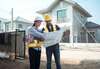 Deux professionnels examinant plans sur site construction maison