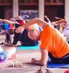 Homme en t shirt orange pratiquant une séance de yoga d entreprise en extérieur pour prévenir les troubles musculo squelettiques