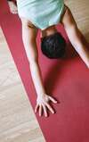 Personne en posture de yoga sur tapis rouge illustrant atelier bien-être en entreprise à Lyon