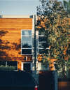 Maison moderne en bois orange ombragée arbres proche chantier