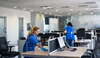 Femme en uniforme bleu nettoyant un bureau moderne en horaires décalés